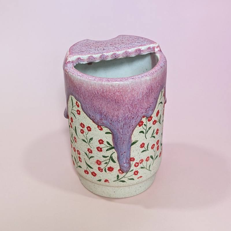 The back of the sippy cup showing long flowing drip of glaze that transitions from a reddish pink to a purple color.