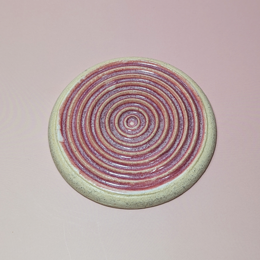 The image shows a dark pink glaze settling into the ridges of the grater.