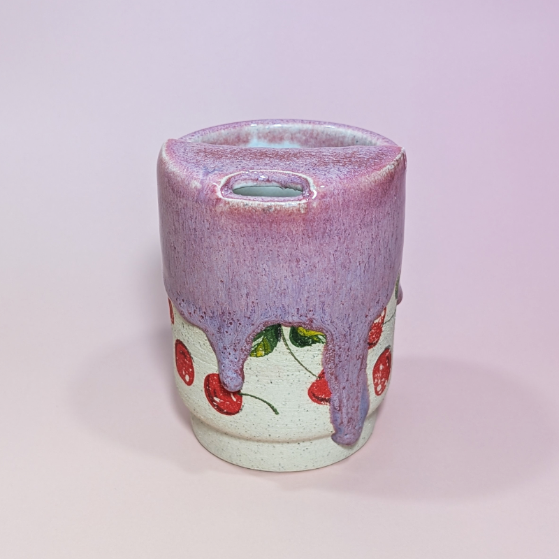 The front of a cherry sippy cup with showcasing the long drips of sangria red and purple glaze.