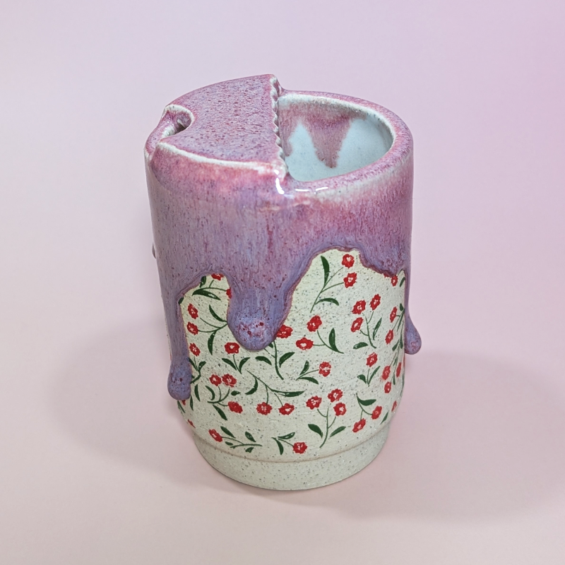 A side view showing the light color body clay with little red poppy flowers and green leaves.