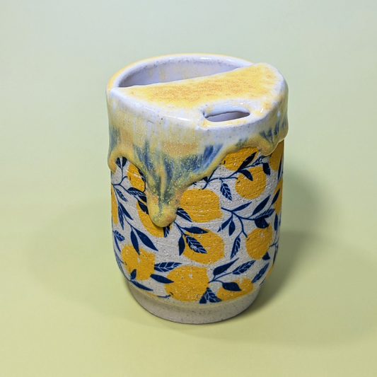 A lemon patterned sippy cup with a runny yellow glaze. This image shows where you drink from.