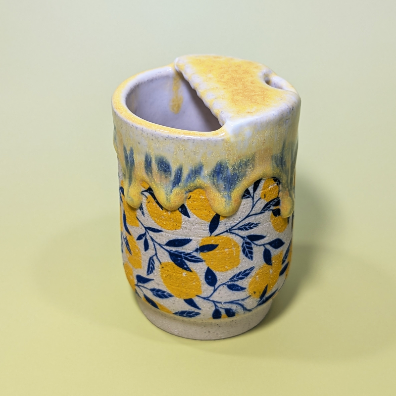 Another view showing the scalloped edge of the lid. The yellow glaze drips and smears the blue leaf pattern beneath it.