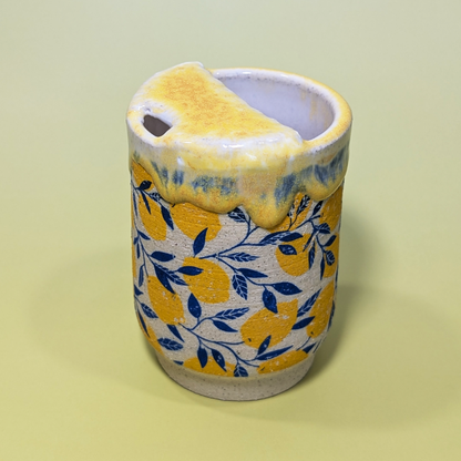 A 3 quarter view of the sippy cup. The side of the cup has a lemon and leaf pattern that wraps around the cup.