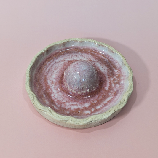 Shows the scalloped shaped rim of the trinket dish with a sculpted strawberry in the center.